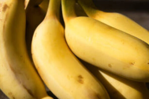 Small cluster ripe, yellow bananas placed on floor in sunlight